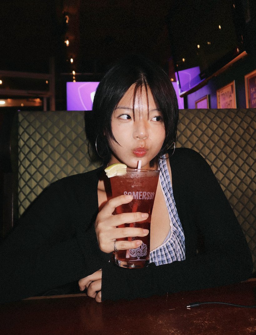 Jean at a bar, sipping a red drink
